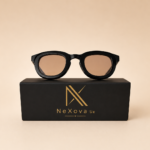 Black round unisex sunglasses from NeXova UK with glossy black frame and warm brown lenses displayed on branded box