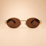 Front view of gold oval sunglasses with warm brown lenses and black side arms