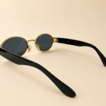 Front view of gold oval sunglasses with smoke black lenses and black side arms