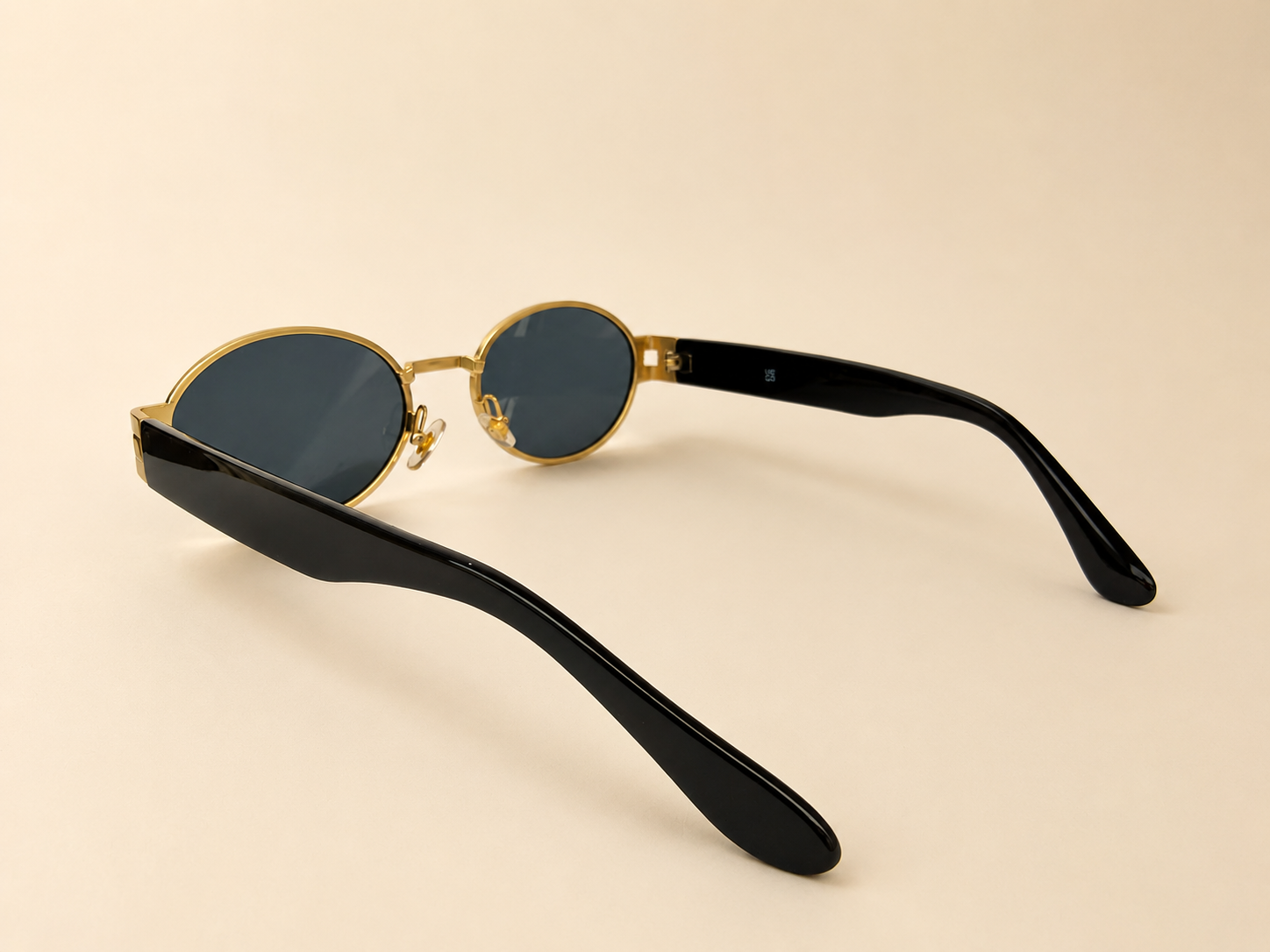 Front view of gold oval sunglasses with smoke black lenses and black side arms