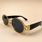 Front view of gold oval sunglasses with smoke black lenses and black side arms