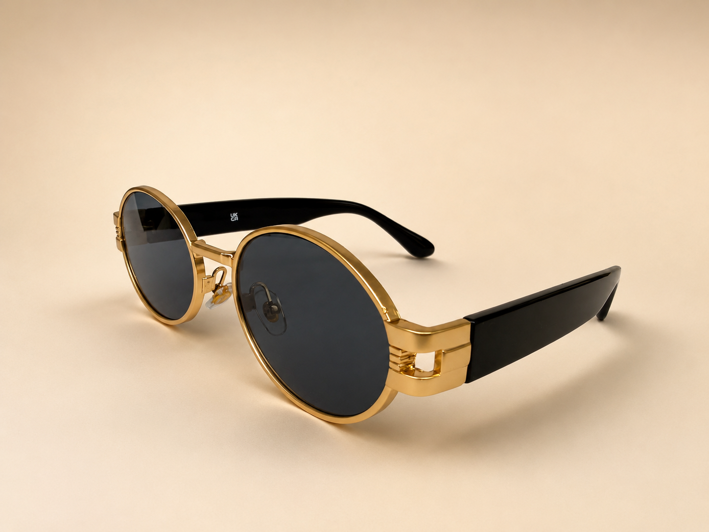 Front view of gold oval sunglasses with smoke black lenses and black side arms