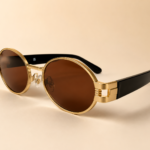 Front view of gold oval sunglasses with warm brown lenses and black side arms