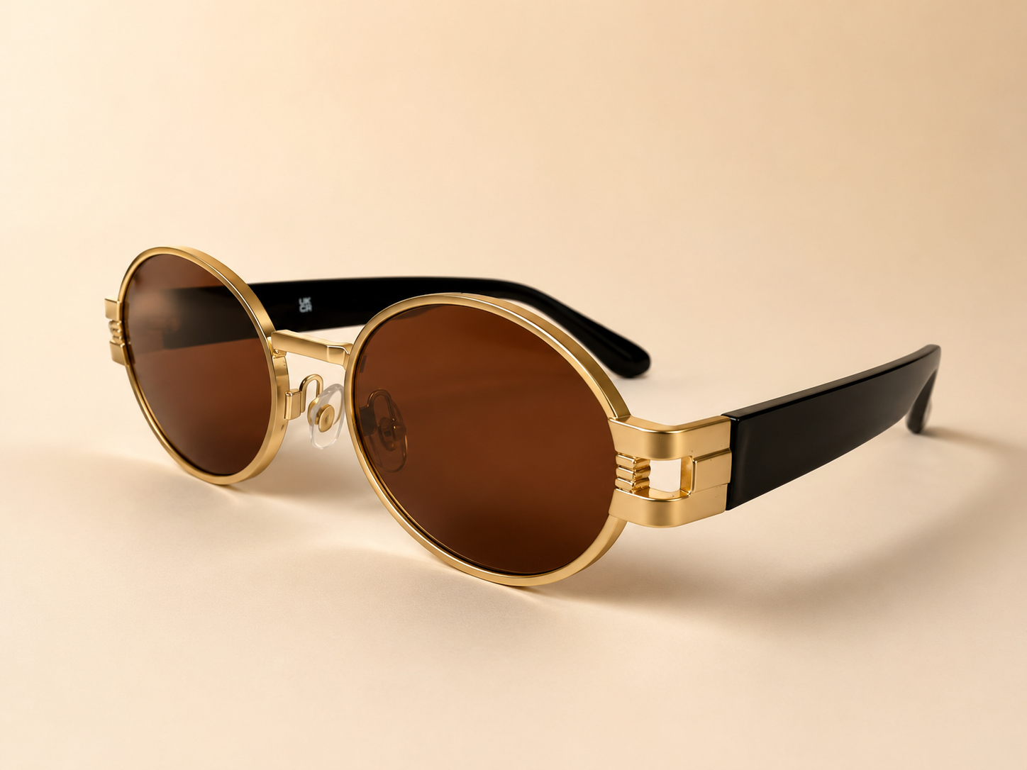 Front view of gold oval sunglasses with warm brown lenses and black side arms