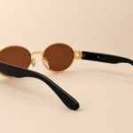 Front view of gold oval sunglasses with warm brown lenses and black side arms