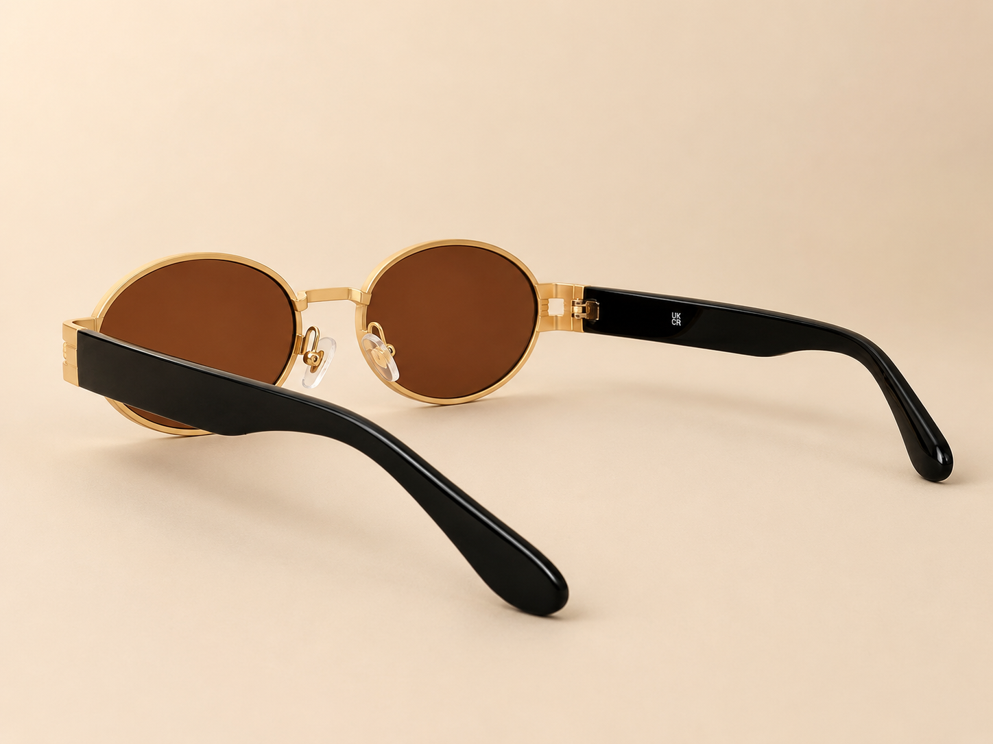 Front view of gold oval sunglasses with warm brown lenses and black side arms
