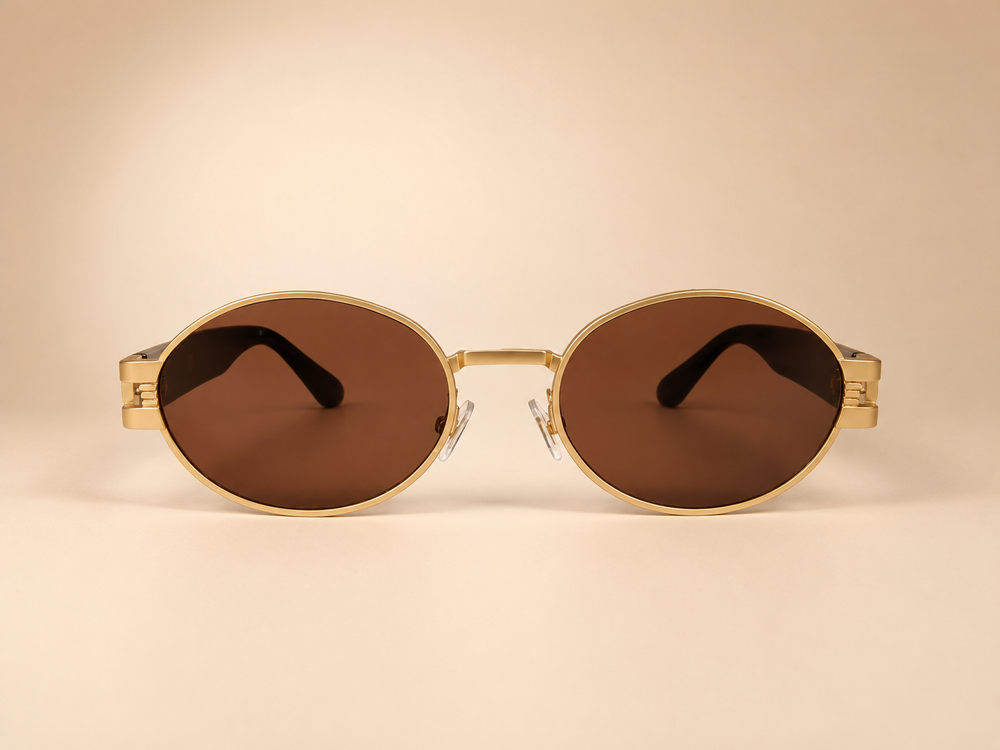 Front view of gold oval sunglasses with warm brown lenses and black side arms