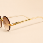 Rimless oval unisex sunglasses from NeXova UK with warm brown lenses, gold-tone bridge and cream temples