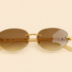 Rimless oval unisex sunglasses from NeXova UK with warm brown lenses, gold-tone bridge and cream temples