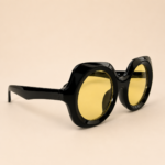 Black round unisex sunglasses with glossy black frame and yellow tinted lenses
